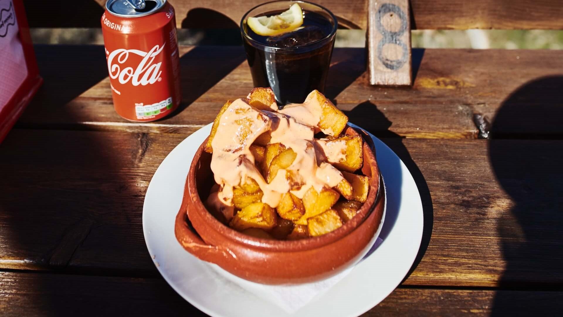 Patatas bravas, un popular plato de tapas español, con patatas fritas cubiertas con salsa de tomate picante y alioli, este plato le llevará a un viaje culinario.